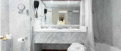 A modern bathroom with two sinks, a hairdryer, a mirror, and a shower.