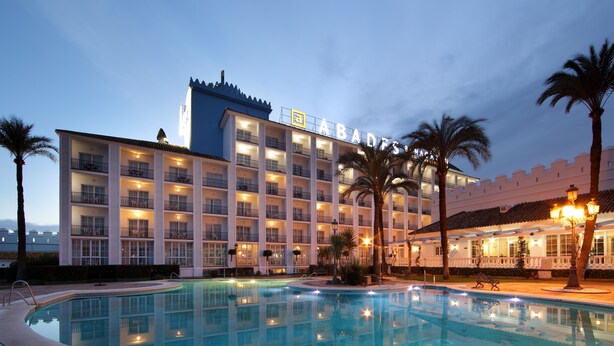 Un hotel con piscina, varios balcones y una fachada bien iluminada.