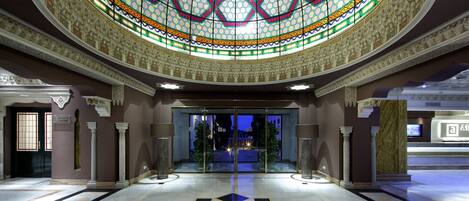 A grand lobby with a star-patterned floor, a large stained glass ceiling, and a modern reception area.