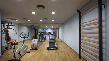 A gym with exercise equipment, a treadmill, and a mirrored wall.