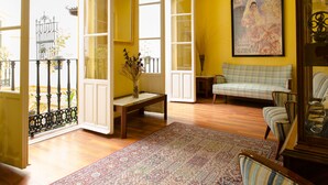 Una habitación con suelo de madera, un sofá a cuadros, un tapiz estampado y un cuadro en la pared.