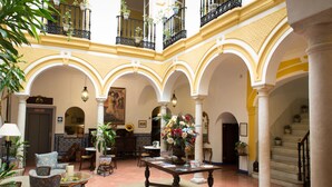 Un vestíbulo espacioso con techo alto, varios arcos y una mesa central con un arreglo floral.