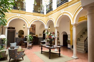 Un vestíbulo espacioso con techo alto, varios arcos y una mesa central con un arreglo floral.