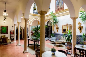 Un patio amplio con columnas, plantas en macetas y un área de comedor con mesas y sillas.