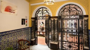 Un vestíbulo de hotel con puertas de hierro negras ornamentadas, suelo de baldosas y un cartel del Hotel Abarico.