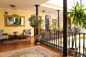 Un salón espacioso con un espejo grande, dos sillones estampados, una mesa de centro y una alfombra decorativa.