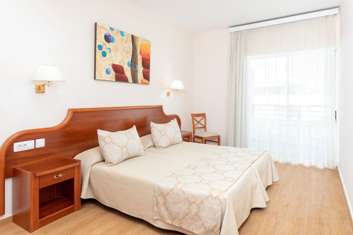 Une chambre à coucher bien rangée, avec un lit en bois, des tables de chevet et un tableau accroché au mur.