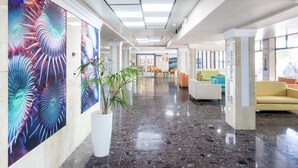Un hall d’entrée moderne avec un sol en marbre, des œuvres d’art colorées et des espaces aménagés pour s’asseoir.
