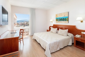 Camera d'albergo con un letto, una scrivania, una sedia e vista sulla città.