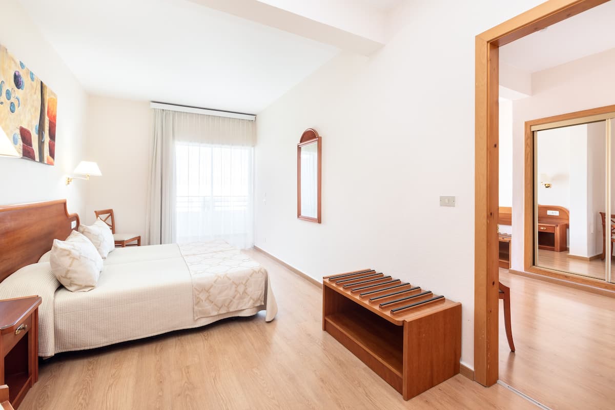 Une chambre à coucher avec un lit, une table de chevet, une lampe et un banc en bois.