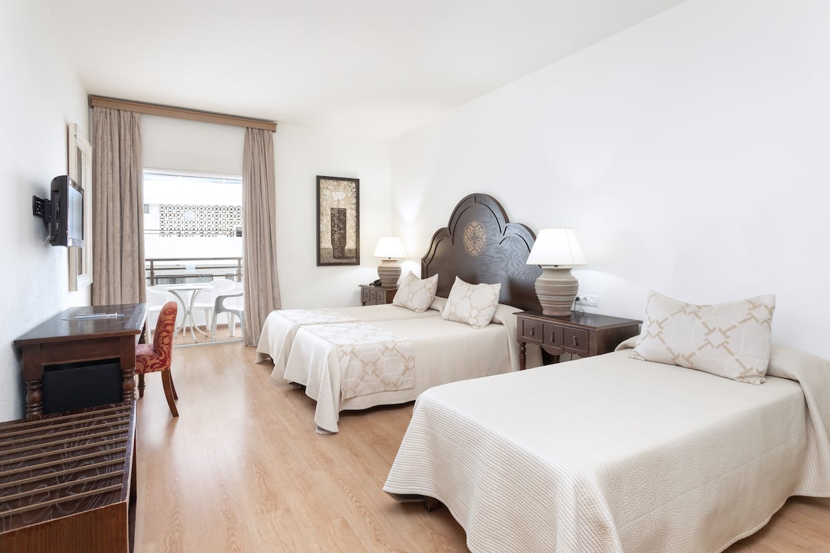 Une chambre d’hôtel avec deux lits, un bureau, une chaise et un téléviseur.