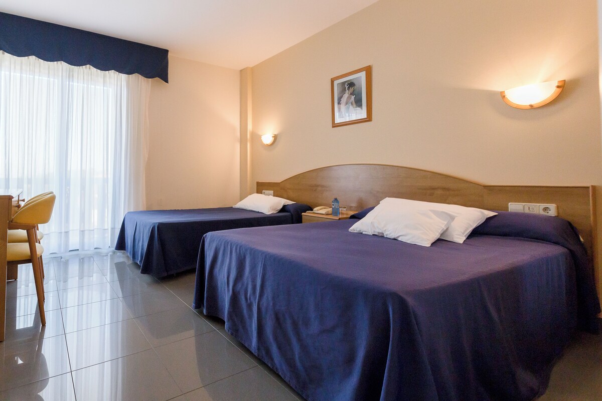 Una habitación de hotel con dos camas, un escritorio y una silla.