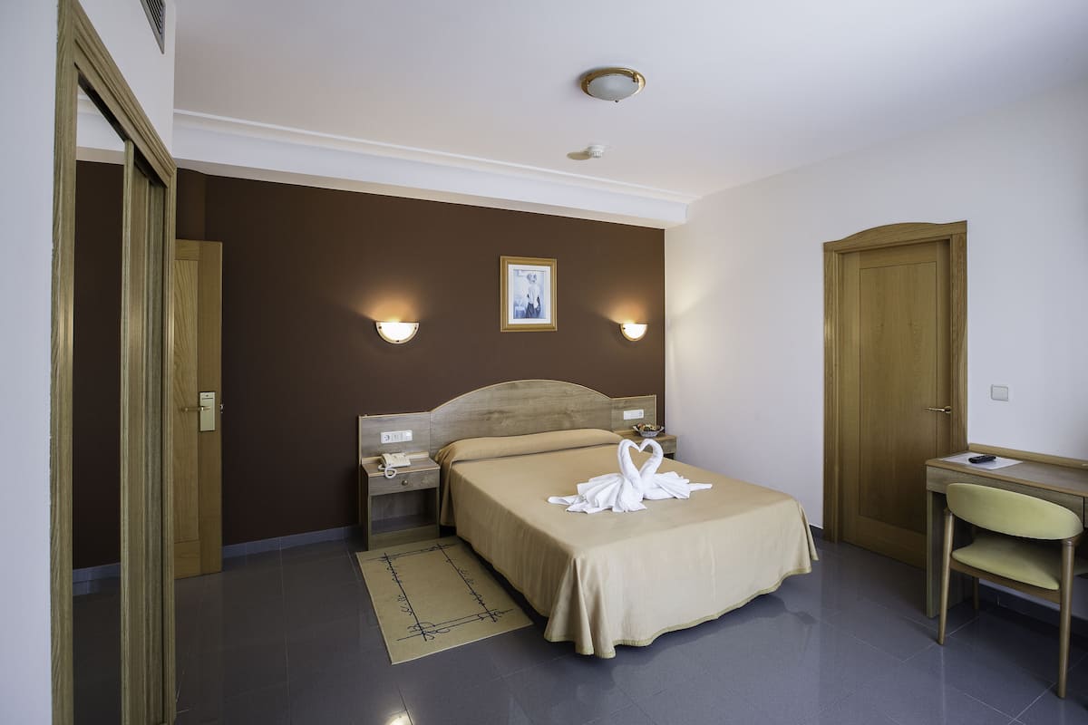Een hotelkamer met een bed, nachtkastjes, een bureau en een stoel.