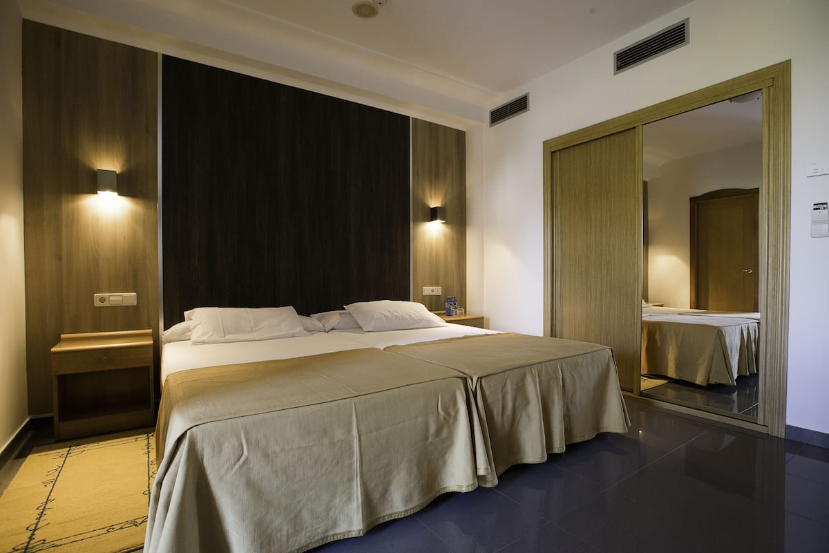 Een hotelkamer met een groot bed, twee nachtkastjes, een spiegel en een kledingkast.