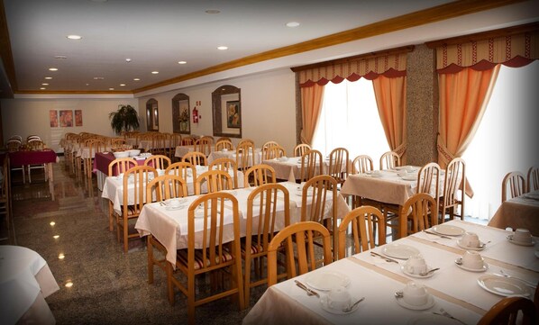 Un comedor con varias mesas y sillas dispuestas en filas.