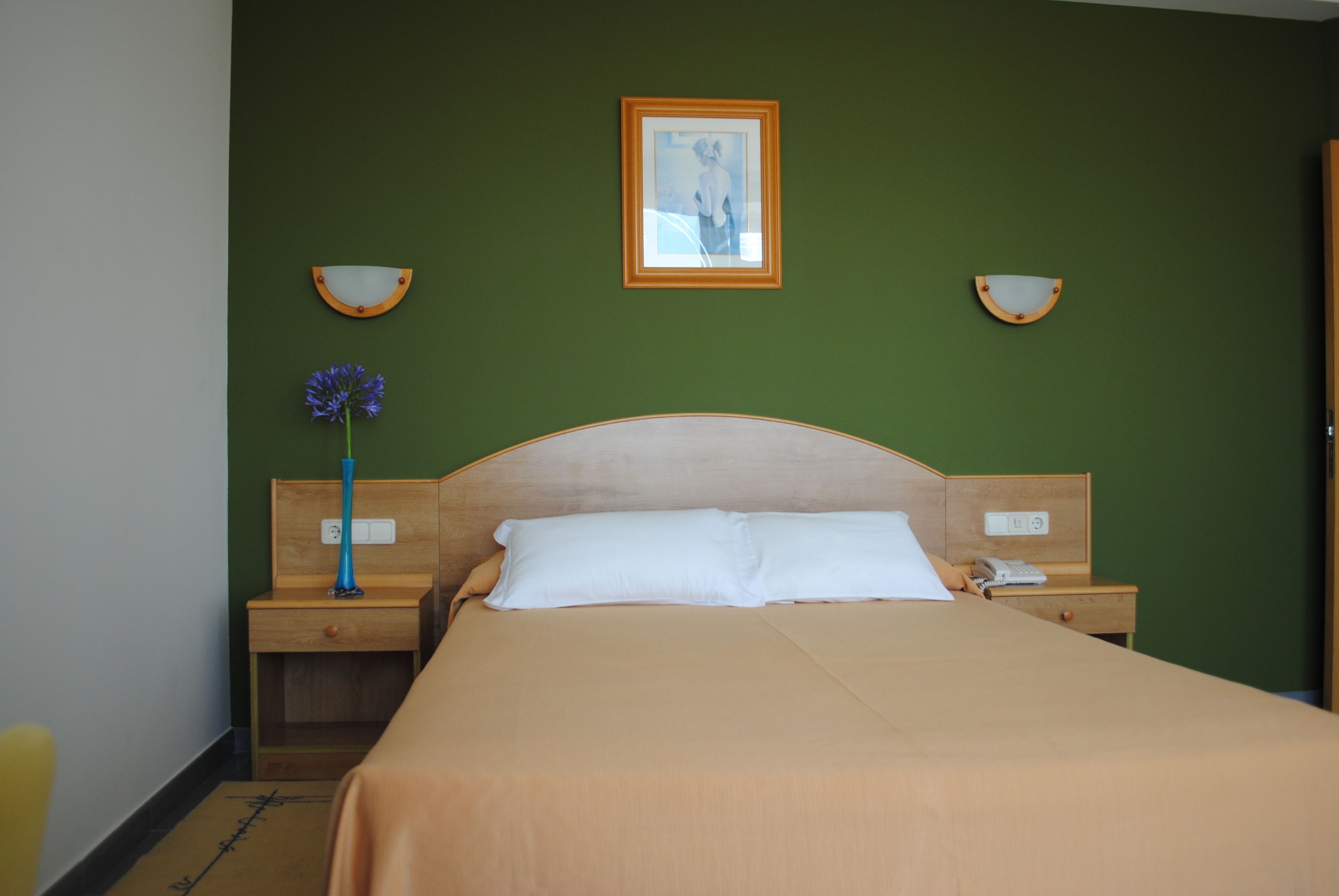 Une chambre d’hôtel avec un lit, une table de chevet, une lampe et un tableau encadré au mur.