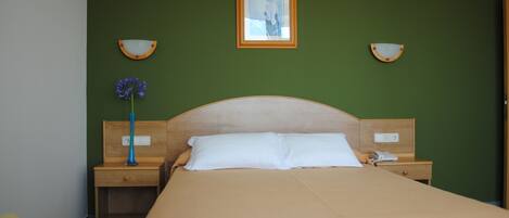 Une chambre d’hôtel avec un lit, une table de chevet, une lampe et un tableau encadré au mur.