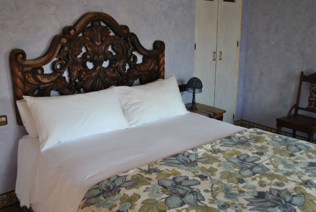 Una cama con colcha estampada de flores y cabecera de madera.