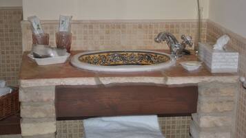 Une salle de bain avec un lavabo en pierre, une étagère en bois et un porte-serviettes.
