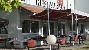 An outdoor restaurant with tables and chairs, a large white spherical decoration, and a building with a 'RESTAURANT' sign.