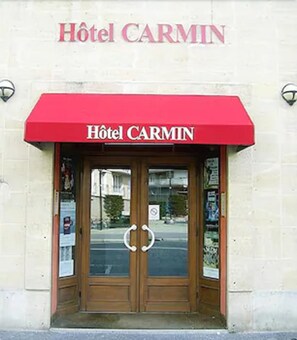 A hotel entrance with a red awning and double doors. - Hotel Carmin (Le Havre)