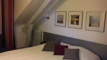 Een slaapkamer met een bed, een radiator en drie ingelijste foto's aan de muur.