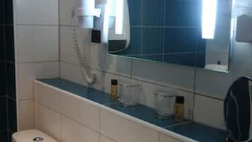 A bathroom with a white sink, a mirror, a hairdryer, and a towel rack.