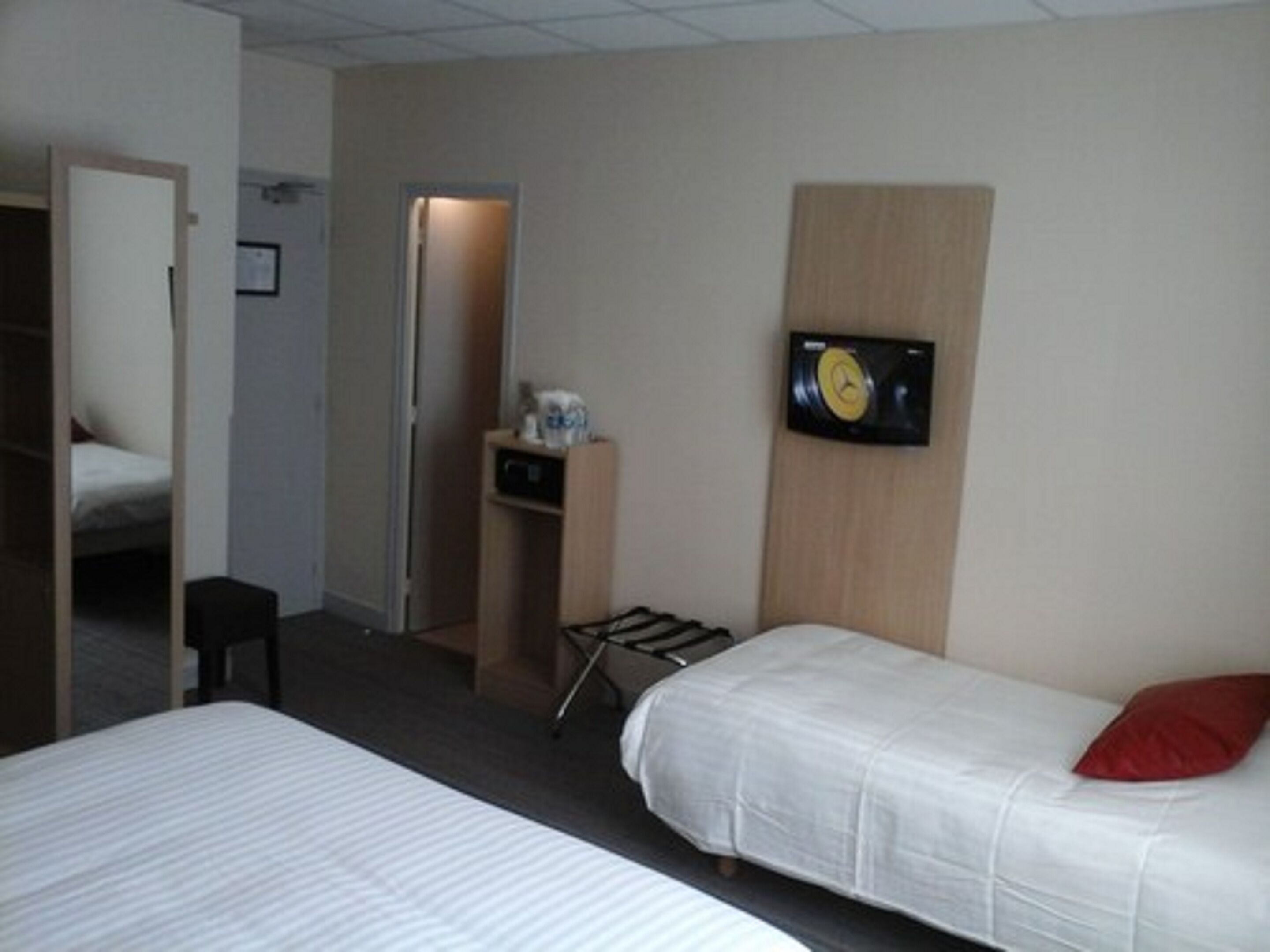 Ett hotellrum med två sängar, en tv på väggen, ett skrivbord och en dörr som leder till ett annat rum.