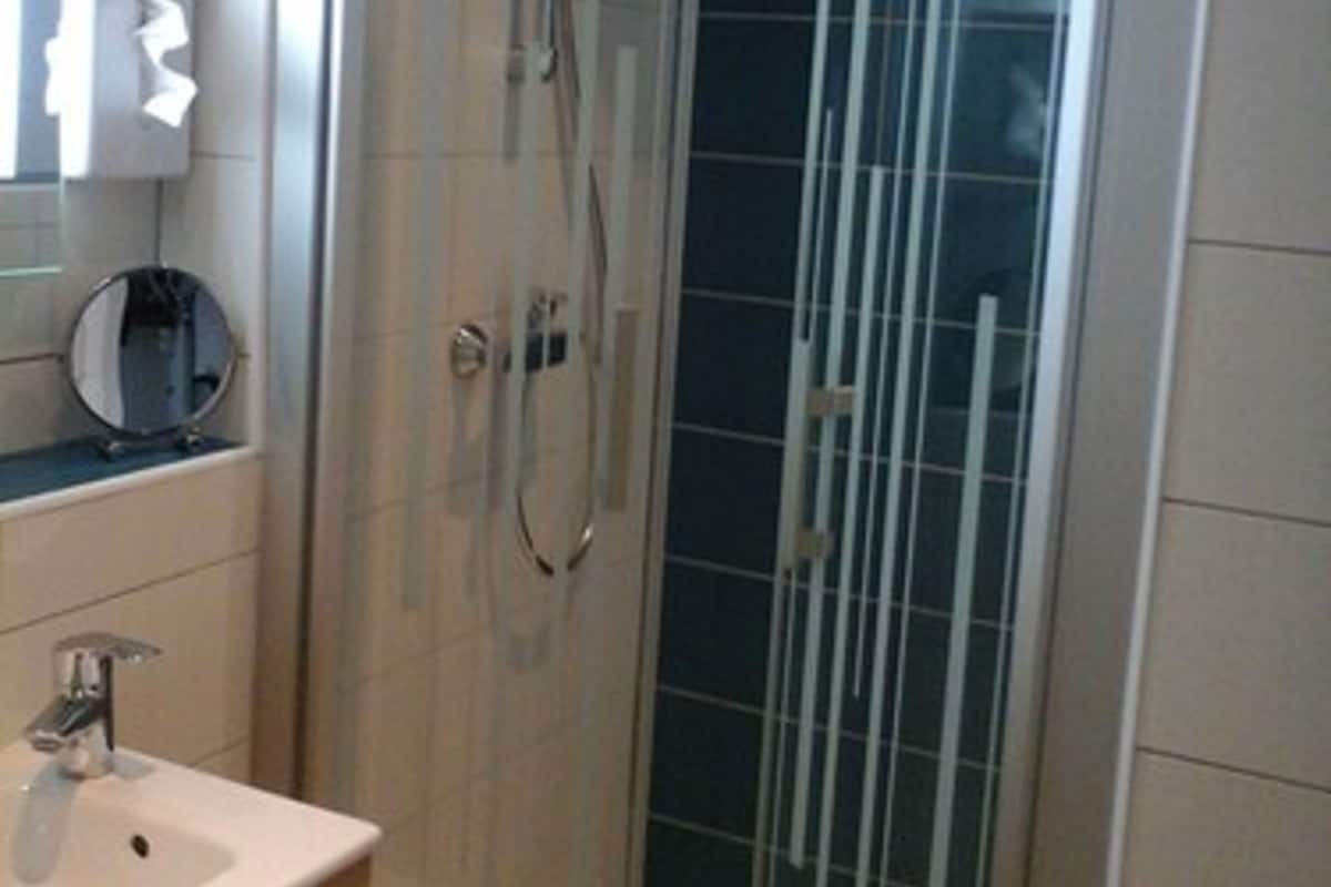 Un baño moderno con cabina de ducha de vidrio, tocador con espejo y lavabo.