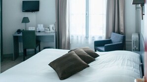 A hotel room with a bed, a desk, a chair, a television, and a window with curtains. - Hotel Carmin (Le Havre)