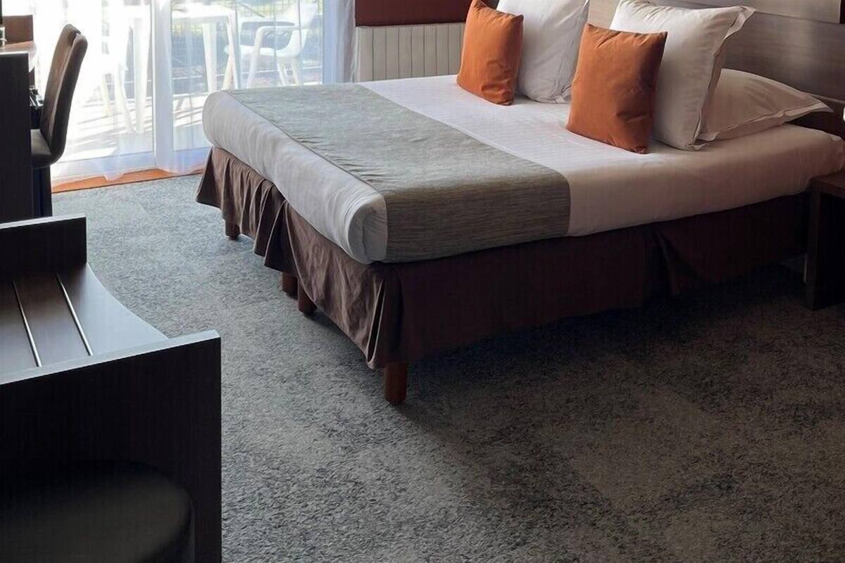 A hotel room with a bed, a desk, and a view of the outdoors.