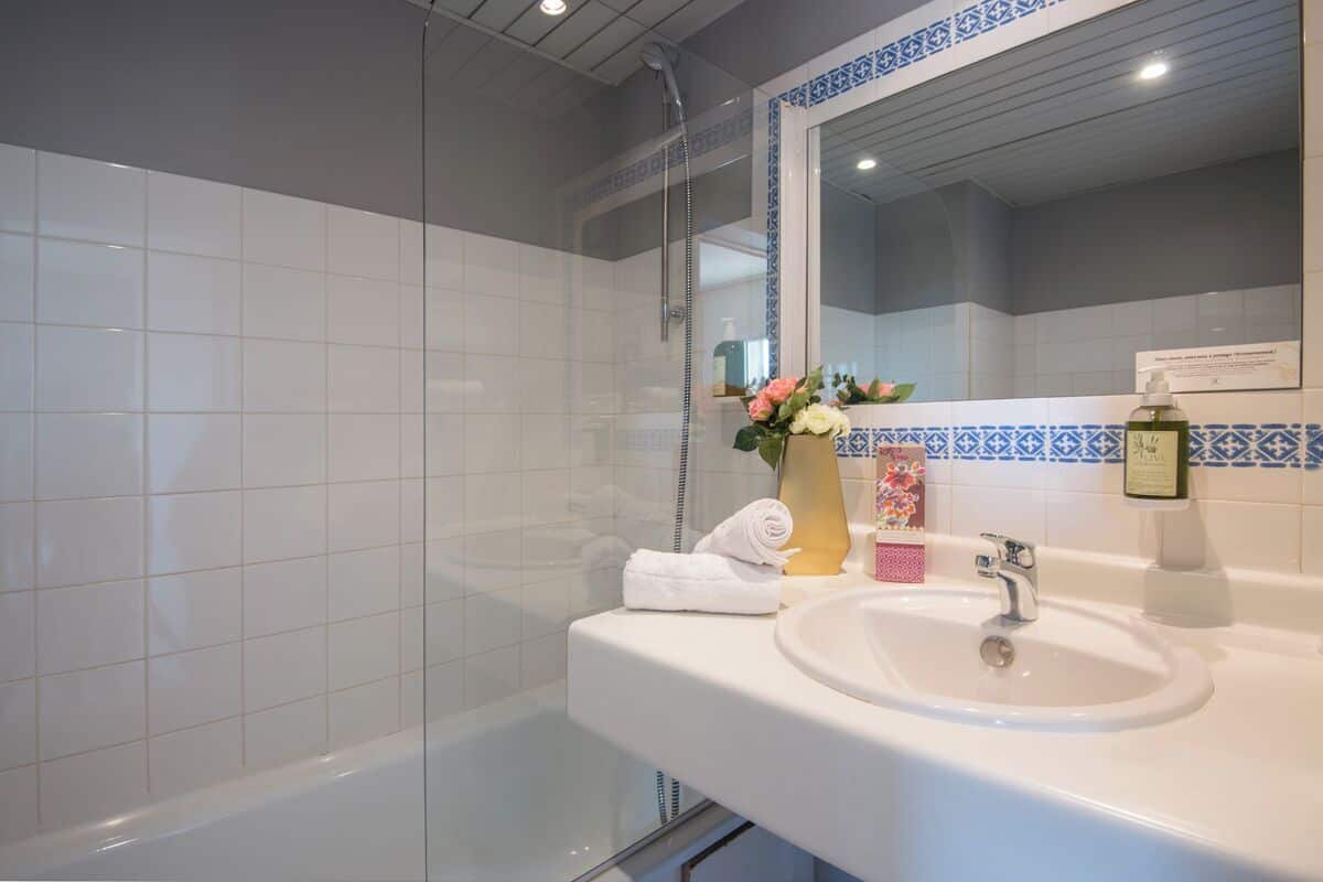 A bathroom with a bathtub, a sink, a mirror, and a shower.