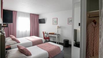 Une chambre d’hôtel avec deux lits, un bureau, une chaise, une télévision et une armoire.