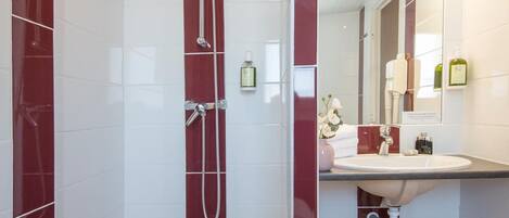 A modern bathroom with a glass-enclosed shower, a vanity with a sink, and a mirror.