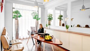 Una cocina moderna con una mesa de comedor de madera, una persona trabajando en un ordenador portátil y plantas en macetas.
