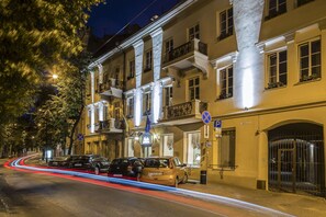 Un edificio de varios pisos con balcones, zona de estacionamiento y entrada protegida por un portón.