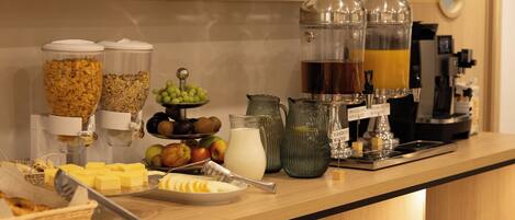 A breakfast buffet with cereal, fruits, milk, and coffee options.