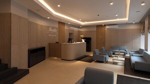 A modern reception area with a reception desk, seating, and a fireplace. - IVOLITA Vilnius Hotel (Vilnius)