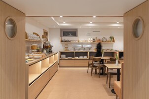 A modern cafe with wooden furniture, a counter with food items, and a seating area.