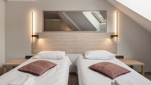 A hotel room with two beds, a skylight, a mirror, and a wall-mounted air conditioner. - IVOLITA Vilnius Hotel (Vilnius)