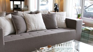 A modern living room with a grey sofa, a glass coffee table, and a cow print ottoman. - Logis Hotel Sully (Nogent-le-Rotrou)