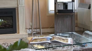 A living room with a fireplace, a television, a floor lamp, and a coffee machine. - Logis Hotel Sully (Nogent-le-Rotrou)