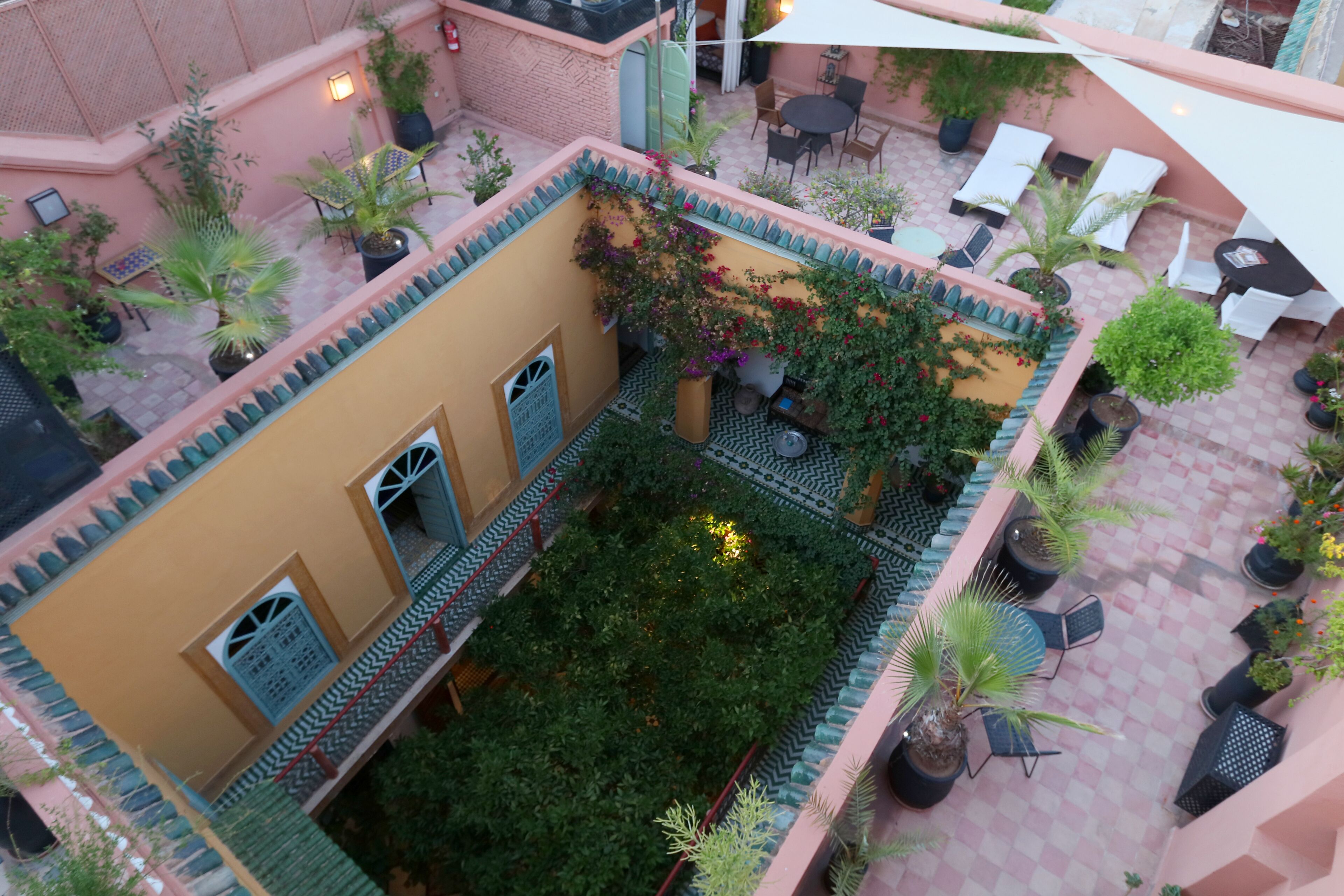 An indoor courtyard with a checkered floor, potted plants, and outdoor seating areas.