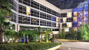 A modern hotel with a multi-level structure, large glass windows, and a landscaped garden area. - Hotel Antares (Villafranca di Verona)