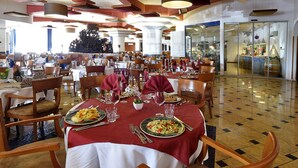 A spacious dining area with multiple tables set for dining, featuring a mix of chairs and tables. - Hotel Antares (Villafranca di Verona)