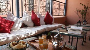 A cozy seating area with a sofa, pillows, a tray with food and drinks, and a table with books and a teapot. - Riad Dar Nimbus (Marrakech)
