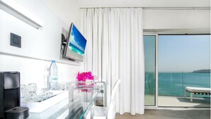A modern hotel room with a glass desk, a flat-screen TV, a water bottle, and a view of the sea. - Hotel Lagon 2 (Dakar)
