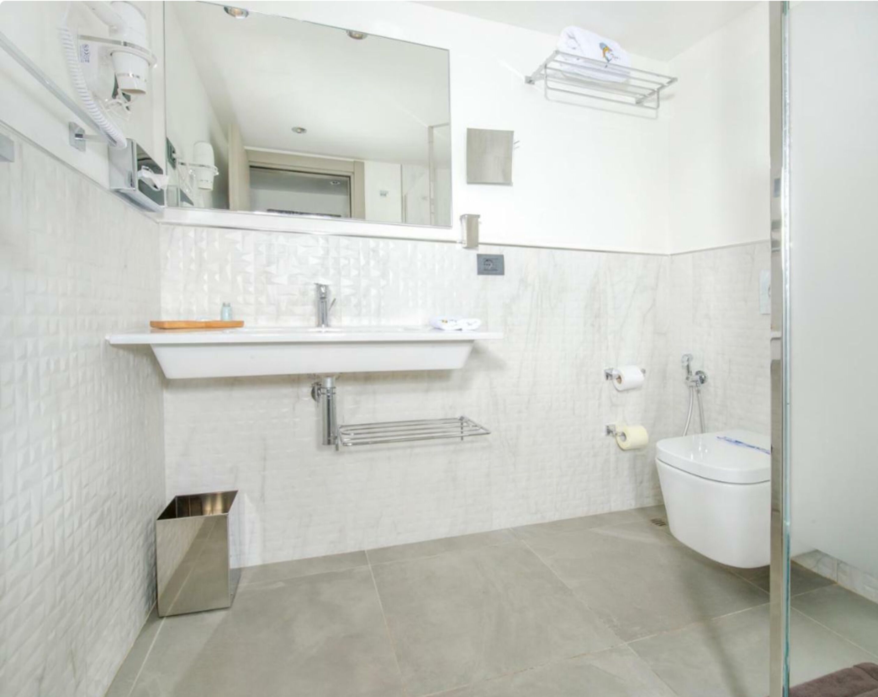A modern bathroom with a white sink, mirror, and toilet.