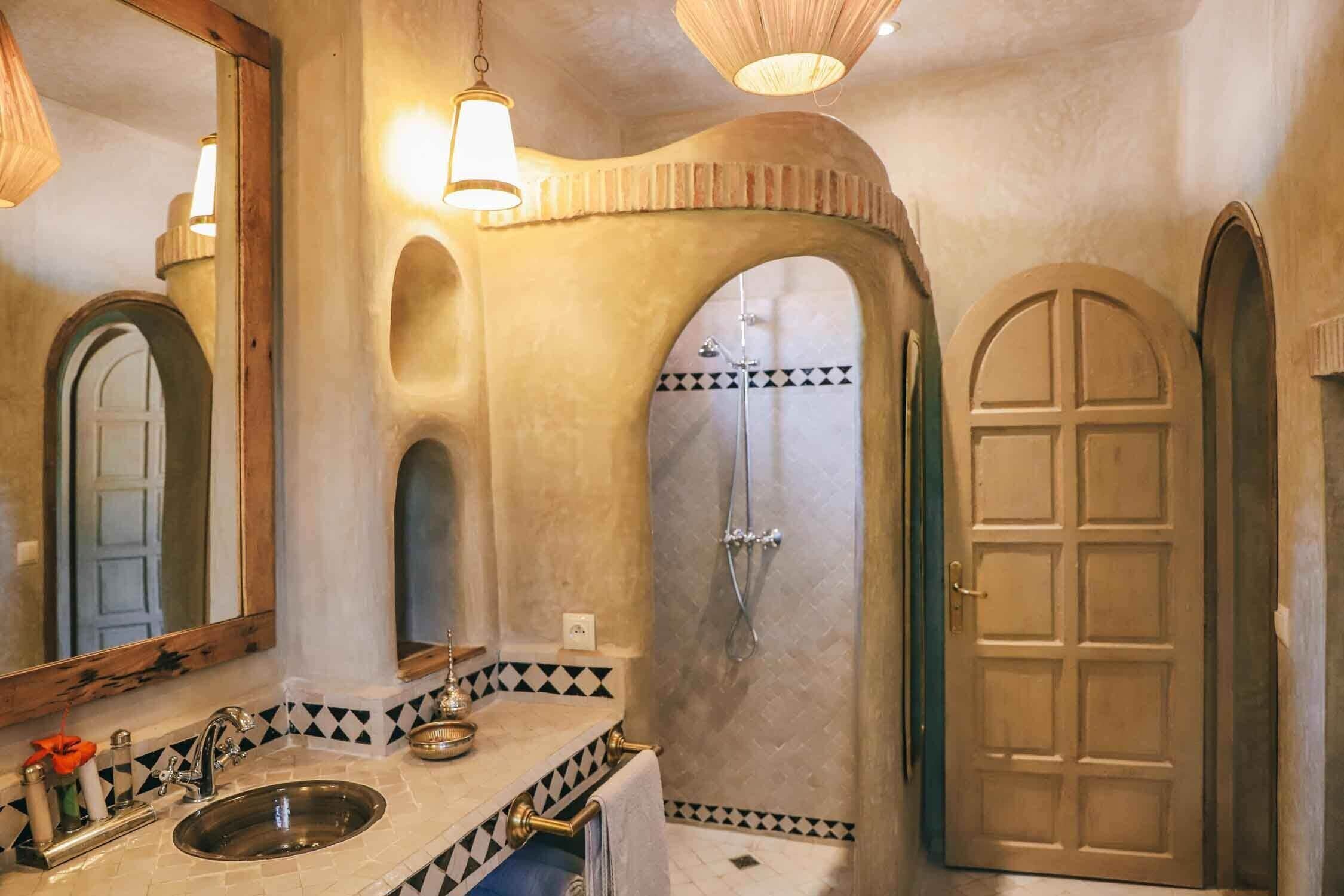 Un baño con lavamanos, espejo, ducha y puerta.