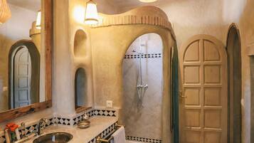 Un baño con lavamanos, espejo, ducha y puerta.